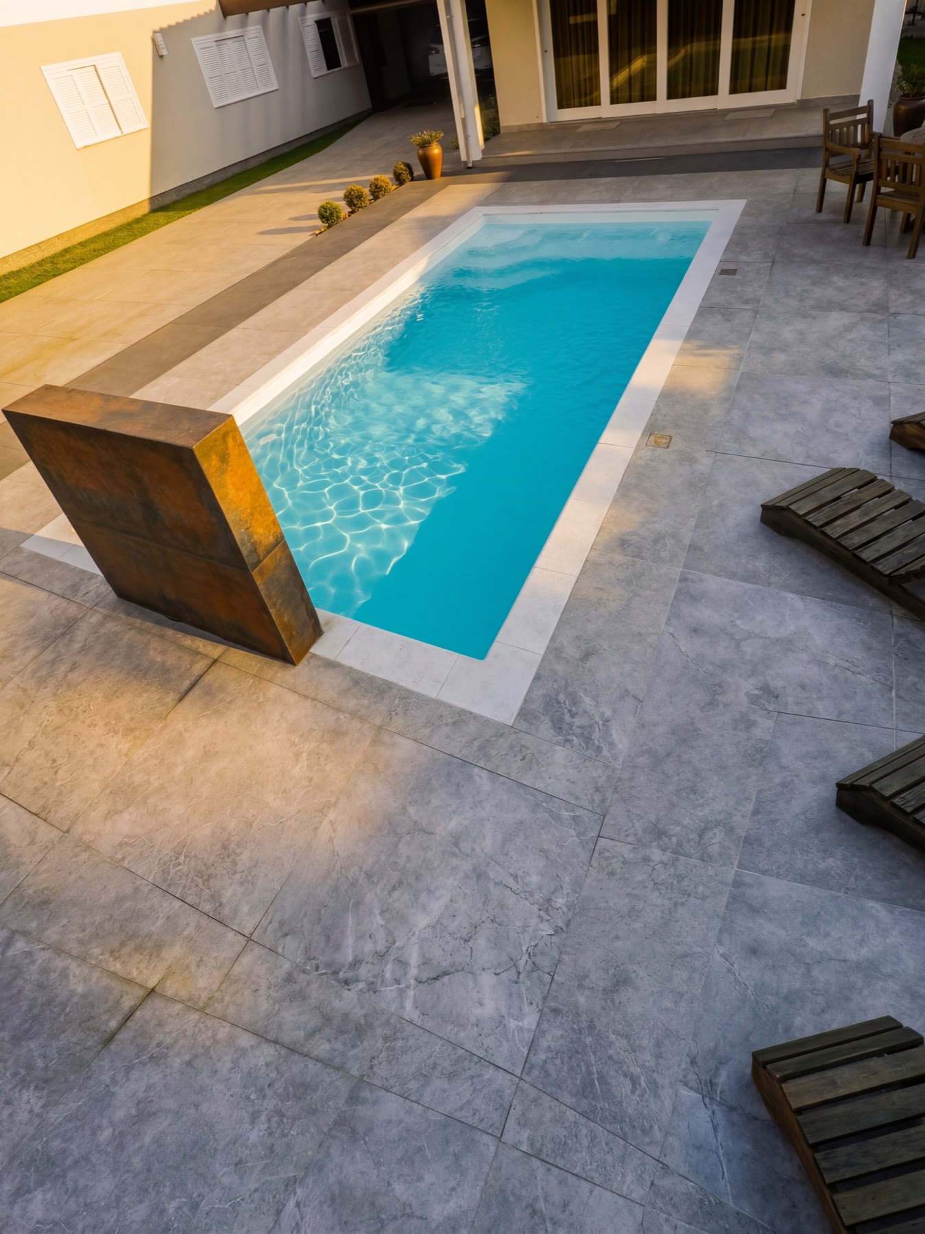 Piscina da Linha Retrô com cascata de pedra corten ao pôr do sol